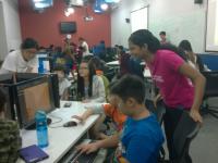 Friendly volunteers assisting young children in game development Friendly volunteers assisting young children in game development